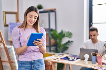Man and woman artists couple using laptop and touchpad drawing at art studio