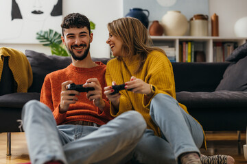 Joyful woman and man are playing video games at home © cherryandbees
