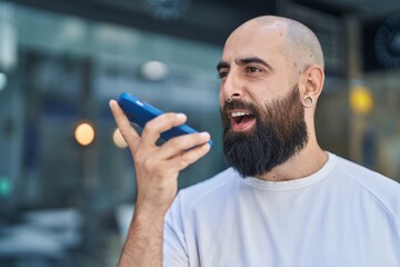 Young bald man smiling confident talking on the smartphone at street