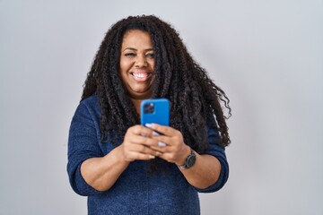 Plus size hispanic woman using smartphone typing message smiling with a happy and cool smile on...