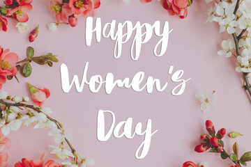 Happy womens day greeting card. Happy womens day text and stylish spring flowers composition on pink background flat lay. Handwritten sign. 8 march International women's day