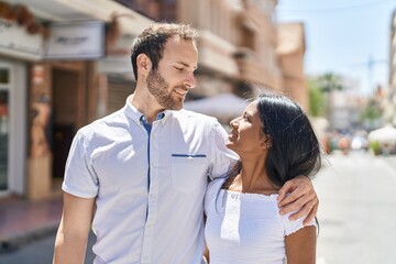 Man and woman interracial couple hugging each other at street