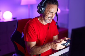 Fototapeta na wymiar Middle age man streamer playing video game using joystick at gaming room
