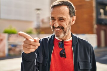 Middle age man smiling confident pointing with finger at street