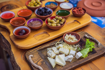 Turkish breakfast table. Pastries, vegetables, greens, olives, cheeses, fried eggs, spices, jams, honey, tea in copper pot and tulip glasses, wide composition