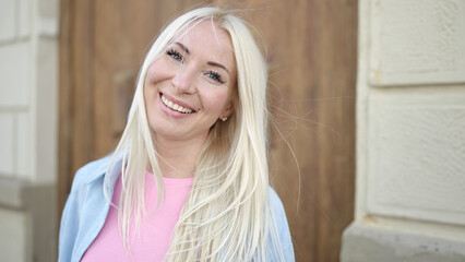 Young blonde woman smiling confident standing at street