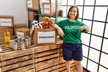 Brunette woman with down syndrome standing by box with donated toys at donations stand