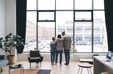 Unrecognizable family hugging near window