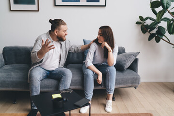 Arguing man sitting with woman on sofa at home