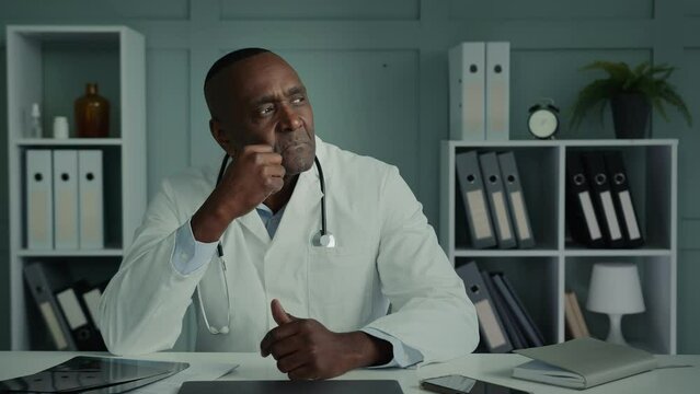 Thoughtful pensive mature adult doctor physician general practitioner african american ethnic elderly man sit at clinic office thinking brainstorming deep thought professional scientist planning idea