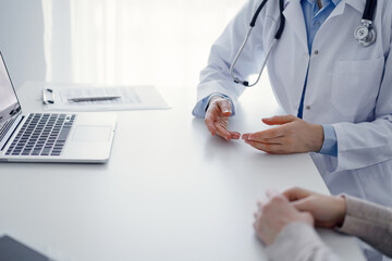 Doctor and patient discussing current health questions while sitting at the table in clinic office, only hands closeup. Medicine concept