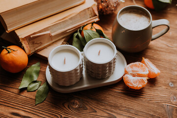 Obraz na płótnie Canvas handmade scented candles, coffee, books and tangerines for the New Year. Cozy atmosphere of Christmas at home
