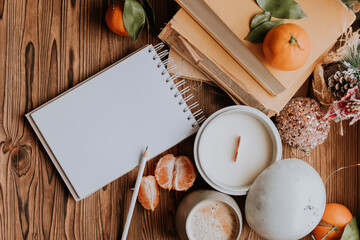 a notebook with blank pages next to books and tangerines, handmade candles. Plans and dreams for the new year