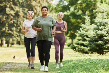 Group of active senior women running towards camera outdoors and smiling