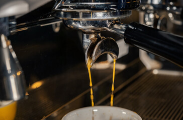 Espresso machine pours fresh black coffee closeup. Coffee machine preparing fresh coffee and pouring into yellow cups at restaurant, bar or pub.