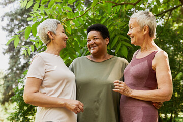 Waist up portrait of three active senior women smiling joyfully outdoors