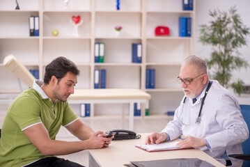 Fototapeta premium Young male patient visiting old male doctor