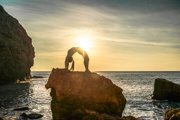 Girl gymnast is training on the beach by the sea sunset. Does twine. Photo series.