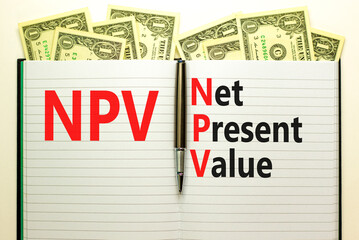 NPV net present value symbol. Concept words NPV net present value on white note on a beautiful background from dollar bills. Pen. Business and NPV net present value concept. Copy space.