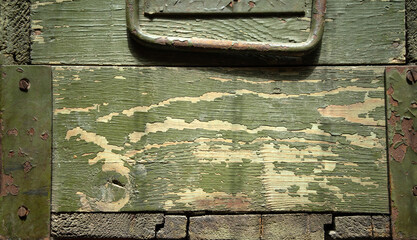 Photo of the texture of a military wooden box from under a weapon.Wooden green background in military style.A green box with a metal handle.