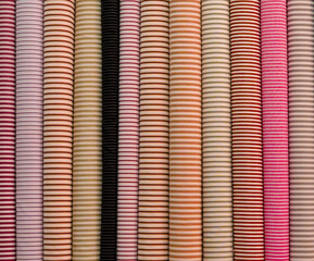 Fabric in rolls of yellow, orange, pink color stands on a shelf in a store, atelier for tailoring