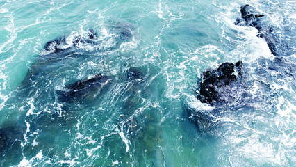 Obraz premium Aerial view of the ocean water surface and waves. Beautiful water background texture for tourism and advertising. Tropical coast