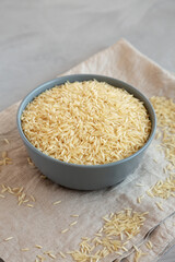 Dry Organic Basmati Rice in a Bowl on a gray background, side view.