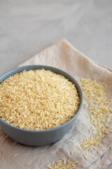 Dry Organic Indian Basmati Rice in a Bowl on a gray background, side view.