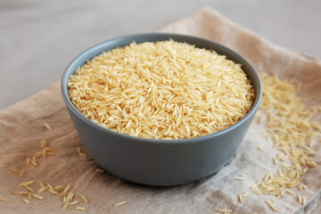 Dry Organic Indian Basmati Rice in a Bowl on a gray background, side view.