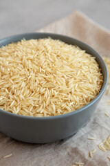 Dry Organic Indian Basmati Rice in a Bowl on a gray background, low angle view. Close-up.
