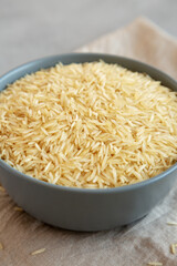 Dry Organic Indian Basmati Rice in a Bowl on a gray background, side view.