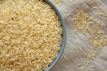 Dry Organic Indian Basmati Rice in a Bowl on a gray background, top view. Flat lay, overhead, from above.