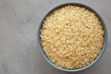 Dry Organic Indian Basmati Rice in a Bowl on a gray background, top view. Flat lay, overhead, from above.