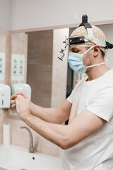 Surgeon with headlight is washing hands before surgery in medical clinic. Hygiene. Correct hand...