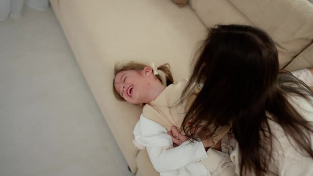 Cheerful mother tickles daughter plays with child for concept of happy family