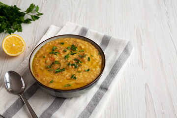 Homemade Lentil Soup with Parsley in a Bowl on a white wooden background, side view. Copy space.