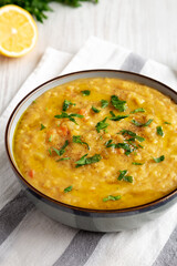 Homemade Lentil Soup with Parsley in a Bowl on a white wooden background, side view.