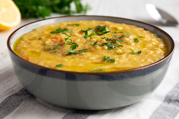 Homemade Lentil Soup with Parsley in a Bowl on a white wooden background, side view. Close-up.