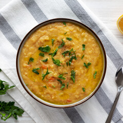 Homemade Lentil Soup with Parsley in a Bowl on a white wooden background, top view. Overhead, from above, flat lay.