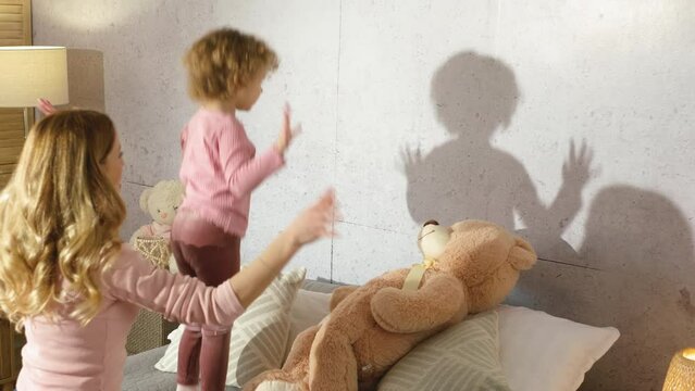 Cute little girl plays with a shadow in bedroom