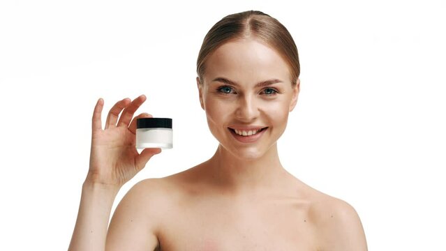 Appealing blonde girl model using a skin care product and smiling of joy in a beauty salon.