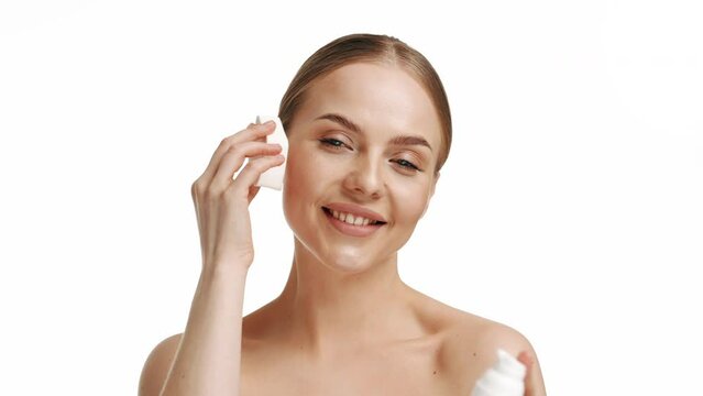 Portrait of a beautiful woman with a sponge. The girl washes her face with a sponge. Fresh clean healthy skin care concept advertisement. A smiling blonde removes her make-up with a cotton pad.