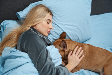 Tranquil lady and her dog resting together in bedroom