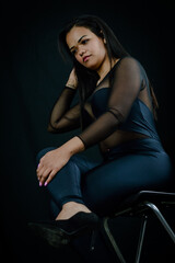 Obraz na płótnie Canvas Portrait of a beautiful young Brazilian woman sitting on a stool and wearing a skintight body suit