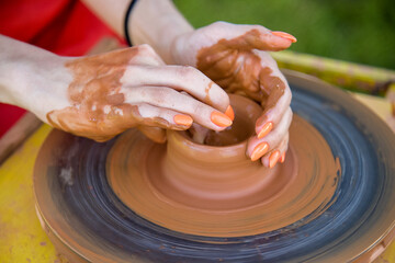 Workshop of ukrainian traditional handmade ceramic pots on the wheel. Hand of master on potter wheel during jar manufacturing.