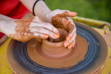 Workshop of ukrainian traditional handmade ceramic pots on the wheel. Hand of master on potter wheel during jar manufacturing.