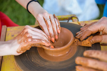 Workshop of ukrainian traditional handmade ceramic pots on the wheel. Hand of master on potter wheel during jar manufacturing.