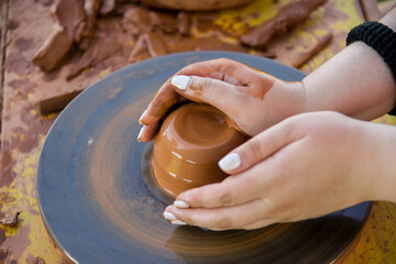 Workshop of ukrainian traditional handmade ceramic pots on the wheel. Hand of master on potter wheel during jar manufacturing.