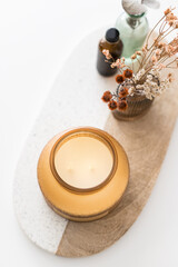 Overhead view of a big twin wick ornamental scented candle over an oval wooden and granite board.