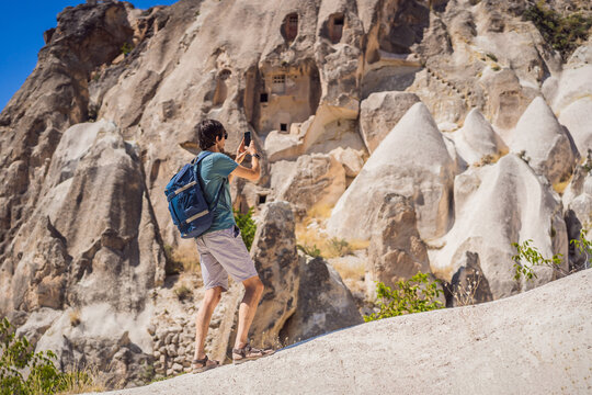 Young man exploring valley with rock formations and fairy caves near Goreme in Cappadocia Turkey